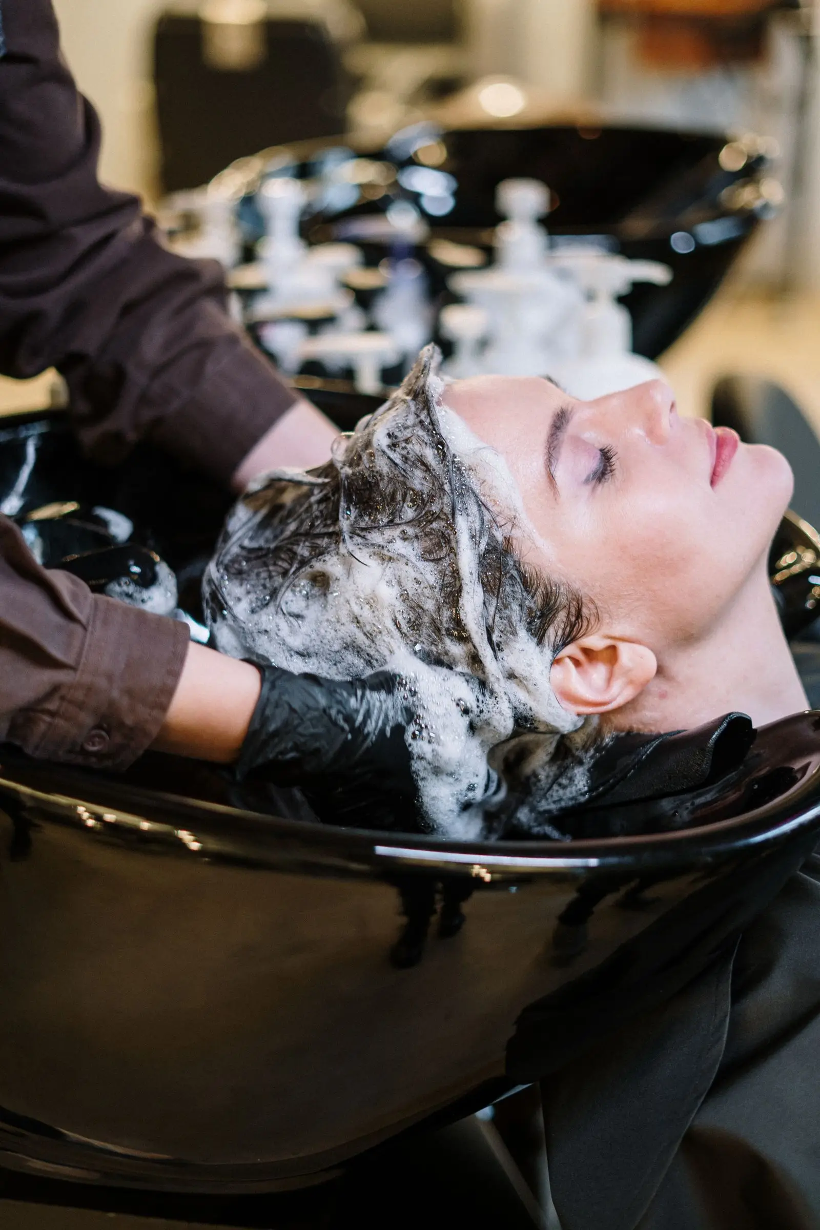 Cliente allongée au bac, shampoing moussant et massage du cuir chevelu