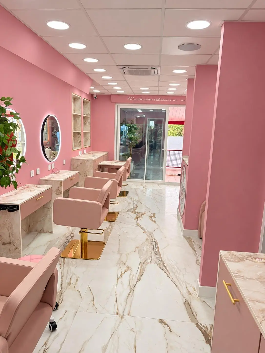 Enfilade de fauteuils de coiffure roses et postes en marbre dans le salon Carrément Belle 2.0